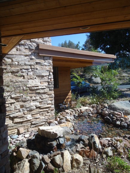 Exterior landscaping featuring river rock pond